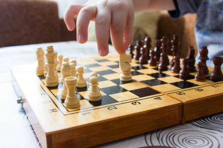 unrecognizable  kid playing chess at home,  closeup of a child's hand moves a chess piece