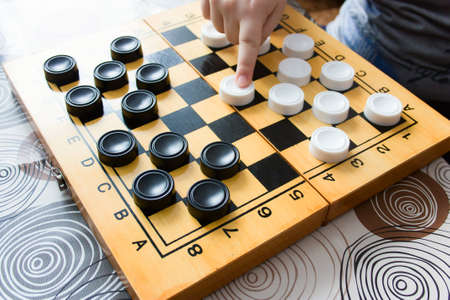 unrecognizable  woman and kid playing checkers at home,  closeup of a child's hand and mother's hand...