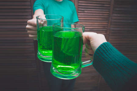 young man with a mug of green ale in a bar opposite a wooden wallの写真素材