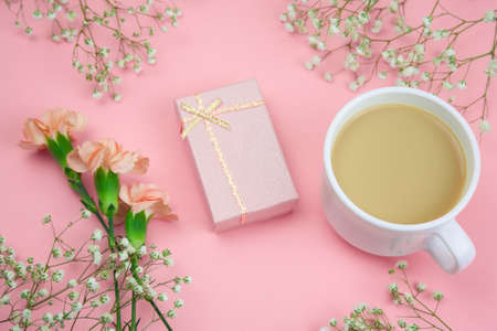 top view flowers, gift box and cup of drink on a vibrant pink background
