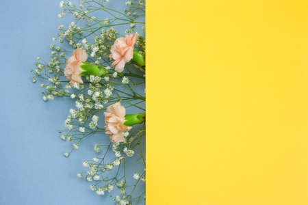 blank yellow paper sheet and bouquet of flowers frame on blue backgroundの写真素材