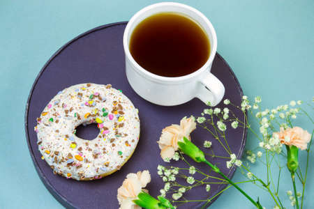 top view cofee mug, donut on a plat and flowers on a blue backgroundの写真素材