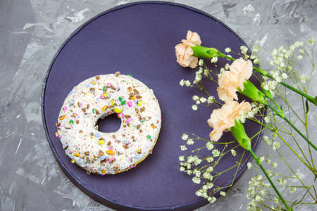 top view donut on a plat and flowers on a conrete backgroundの写真素材