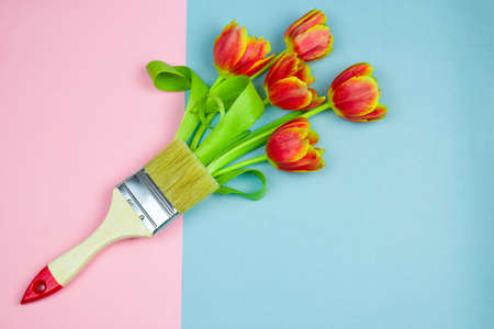 top view flat lay paint brush with bouquet of tulips on a pastel pink and blue background,brush...