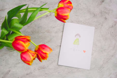 beautiful tulips and handmade card with kid's drawing  for Mother's Day on marble background, top...