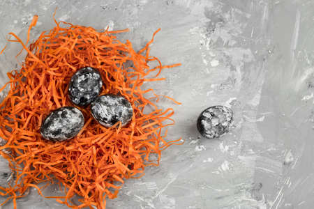 top view dyed eggs with black and white geometric pattern in a decorative orange nest on a concrete...