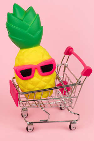 shopping cart with pineapple on pink pastel backgroundの写真素材