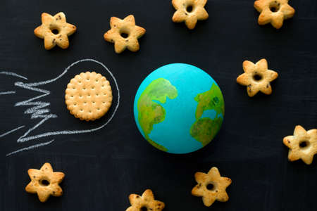 top view  handmade model  of Earth planet, cookie meteorite   and cookies in the shape of stars on the chalkboard , space and astronomy conceptの写真素材