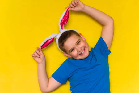 Portrait of a smiling adorable little boy wearing bunny ears isolated over yellow background