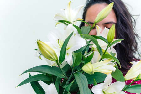bouquet of blooming white lilies in front of a grey shabby concrete wallの写真素材