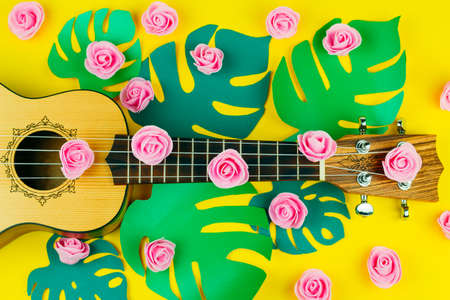 top view of a guitar and rose flowers pattern on vibrant   yellow backgroundの写真素材