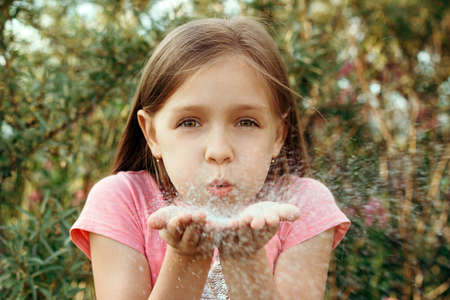 beautiful little girl blow off sequins outdoorの写真素材