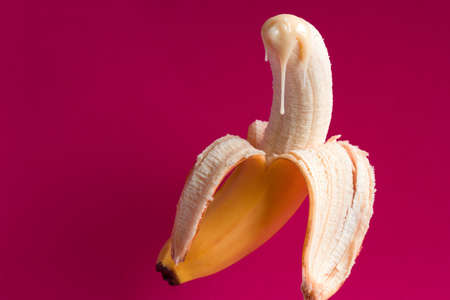 banana and drops of condensed milk on a vivid pink backgroundの写真素材