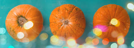 top view flat lay three pumpkins on a blue background with shiny bokeh bannerの写真素材