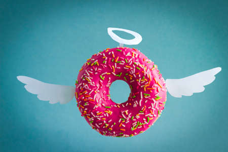 sweet pink  donut with white paper wings and nimbus on a  blue backgroundの写真素材