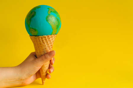 female hand holds waffle cone with Earth model