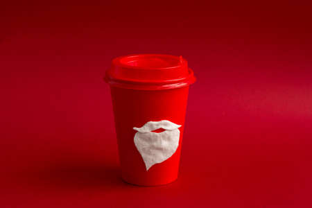 red disposable paper cup for takeaway drinks with  cotton mustache and beard of Santa Claus, winter...