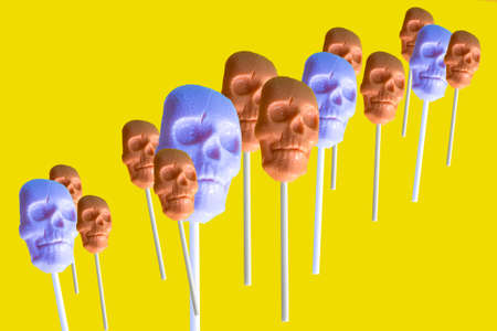 caramel on a stick in the shape of a skull on a yellow backgroundの写真素材