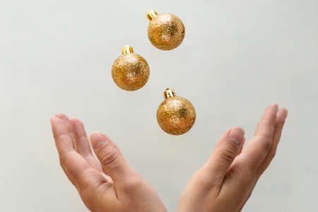 golden christmas balls fly into female handsの写真素材