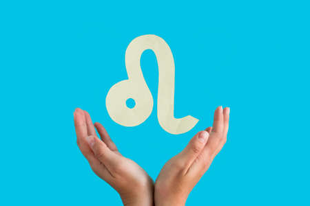 Leo astrological sign hanging over female hands on blue background, horoscope forecast conceptの写真素材