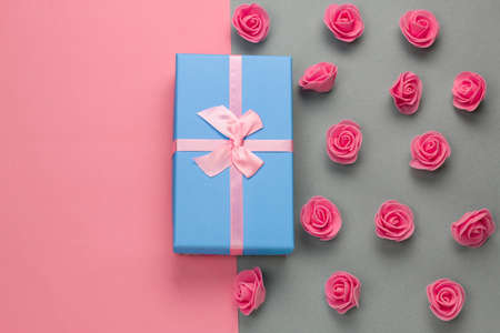 top view blue present box with pink bow and delicate pink roses pattern on a gray and pink...