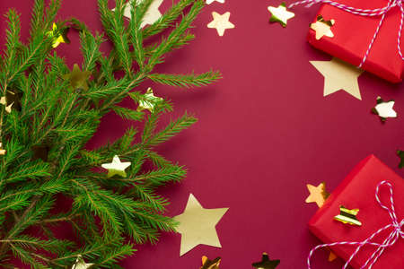 evergreen tree, red gift boxes and  starry confetti on a red background with free space for textの写真素材