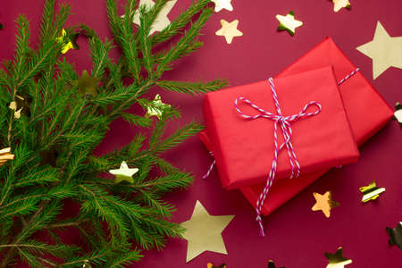 evergreen tree, red gift boxes and  starry confetti on a red background