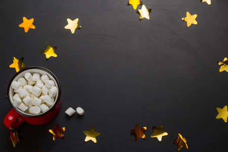 cup with marshmallows and golden confetti on a black background with copy spaceの写真素材
