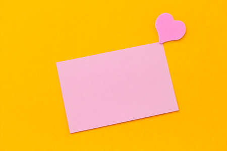 pink blank paper sheet and pink hearts on a yellow background copy spaceの写真素材