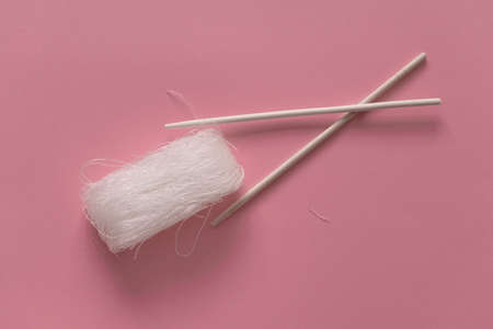 Asian uncooked cellophane noodles  with wooden chopsticks on a pink background top view flat lay