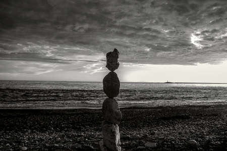 black and white photo pyramid of large stones on the beach at sunsetの写真素材