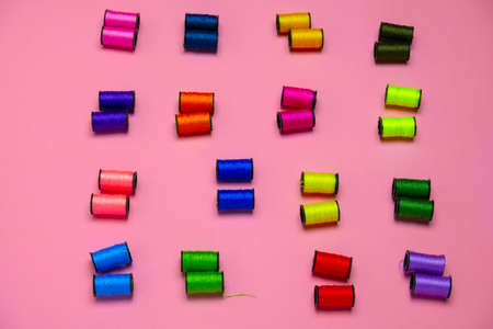 top view creative still life flat lay with reels of multicolored threads pattern on a pink...