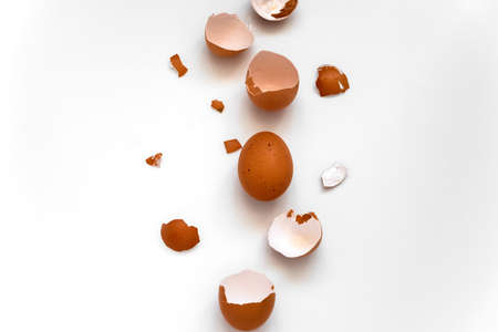 top view flat lay one brown egg and egg shells on a white backgroundの写真素材