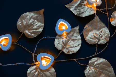 golden leaves and heart shaped garland with yellow lights on a black background