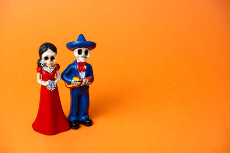 figurine of skeletons of a man and a woman for day of the dead festival  in Mexico on a vibrant orange background, copy spaceの写真素材