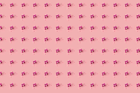 creative pattern tiny gift boxes decorated with pink satin bows and pink hearts on a pastel pink backgroundの写真素材