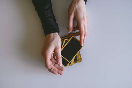 top view stack of fortune telling cards and a woman's hands on a white table, divination and...