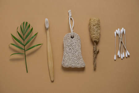 top view flat lay bamboo toothbrush and cotton swabs, pumice and loofah facial sponge on a beige...