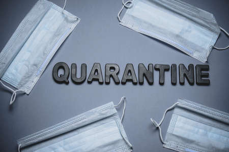top view flat lay medical masks and the word quarantine on a gray backgroundの写真素材