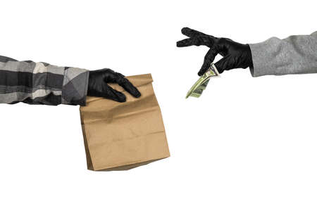 courier's hand in latex gloves holds a paper mock  up bag with food and female hand in latex gloves...
