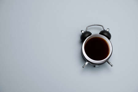 top view black coffee in black alarm clock on a gray background copy spaceの写真素材