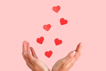 red hearts flying from female hands against pink backgroundの写真素材