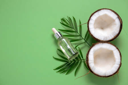 top view cosmetic oil bottle ,coconut and tropical leaf on a green backgroundの写真素材
