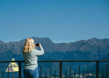 unrecognizable woman with backpack standing on observation deck in mountains blurred backgroundの写真素材
