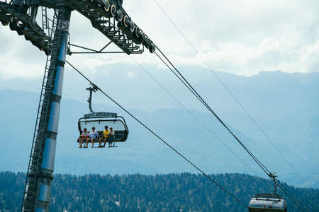 Sochi, Russia, 17 September 2020 - tourist moving in cable car on a blurred background of high mountains in blue haze at the morningの写真素材