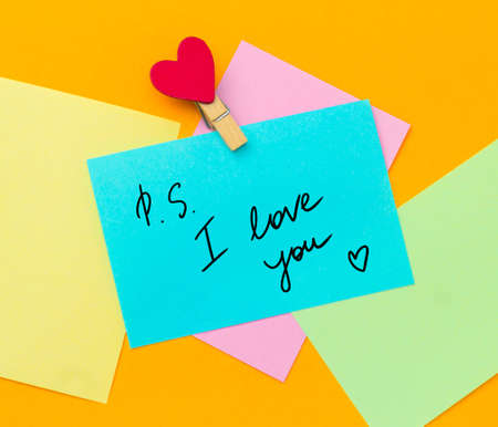 multicolored paper notes with text ps i love you with cloth pin decorated with red heartの写真素材
