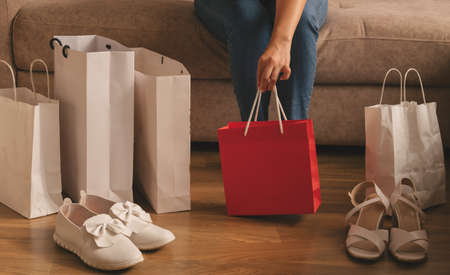a young woman takes out her purchases from a bag while sitting on the sofaの写真素材