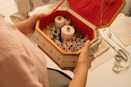 top view female hand holding spools of thread, sewing and sewing production concept