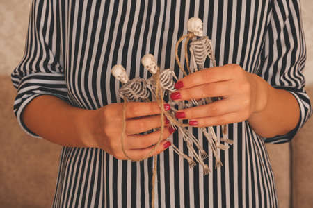 close up female hands holding garland made of skeletons, Halloween preparation conceptの写真素材