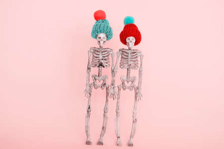 selective focus pair of skeletons wearing cute knitted hat on a pink backgroundの写真素材